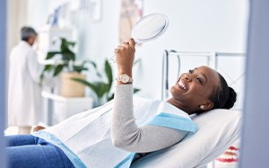 Woman smiling at reflection in handheld mirror