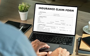 Person filling out insurance claim form on laptop