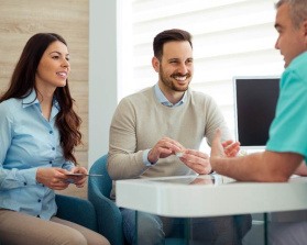 Dentist and couple talking in dental office