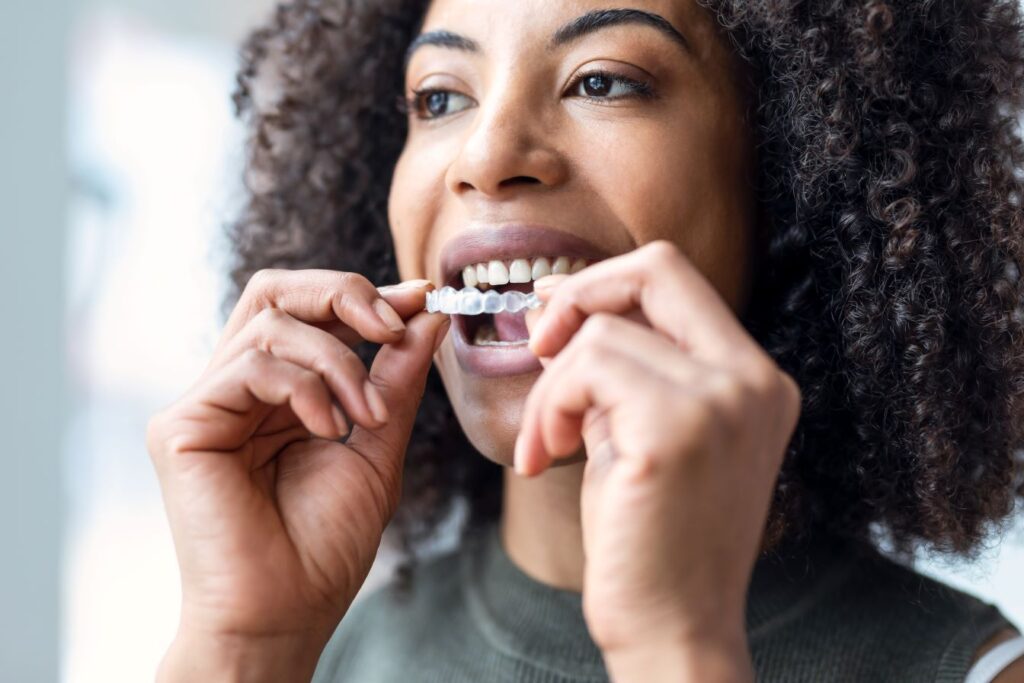 A woman putting on an Invisalign aligner